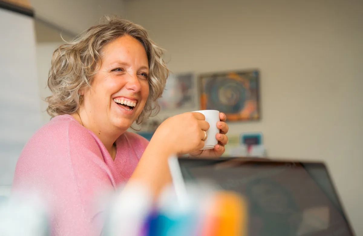 Lachende vrouw met kop koffie in de handen