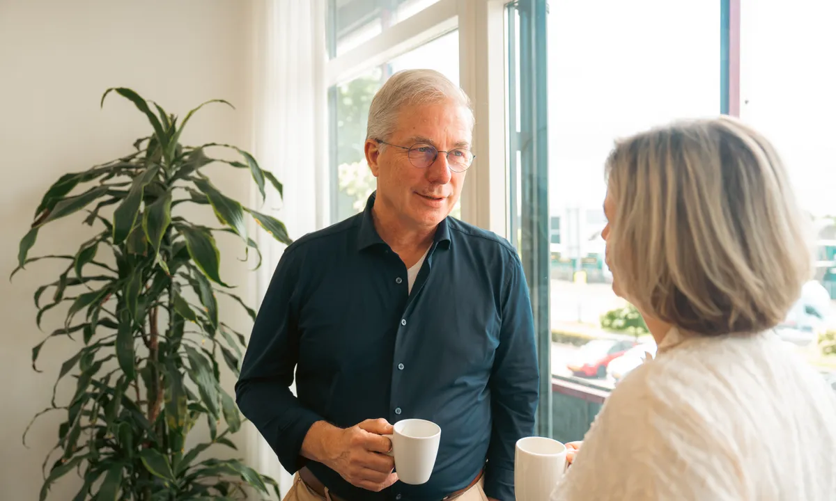 Lachende man met koffiekop in gesprek met organisatie