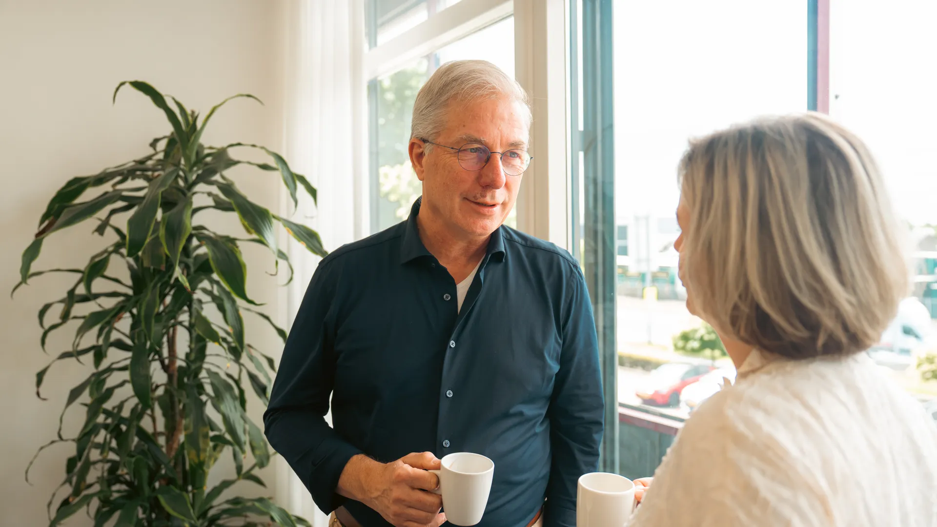 Lachende man met koffiekop in gesprek met organisatie